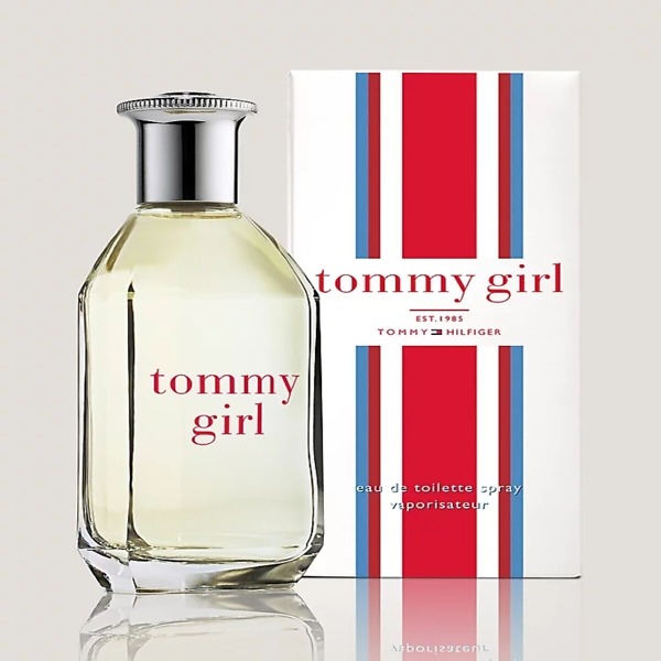 A 50ml bottle of Tommy Girl Eau De Toilette, featuring a sleek transparent glass design with a silver cap. The bottle reflects the fresh, floral, and citrusy fragrance, perfect for vibrant and confident women.